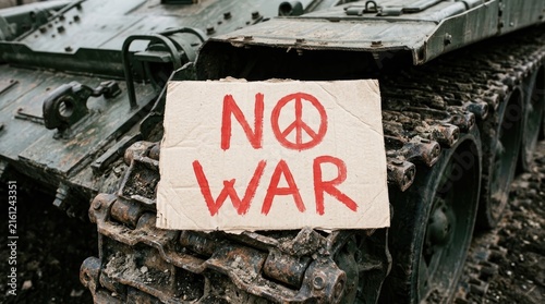 Hand drawn cardboard sign with red ink text reading no war featuring a pacifist symbol placed prominently on top of heavy military tank tracks representing urgent global protest movements