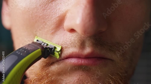 Man Trims Facial Hair Above His Upper Lip With an Electric Razor in an Extreme Close Up, Showing Personal Grooming and Self Care
