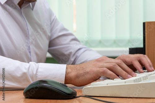 Bild auf Leinwand Office worker typing on keyboard beside computer mouse at desk