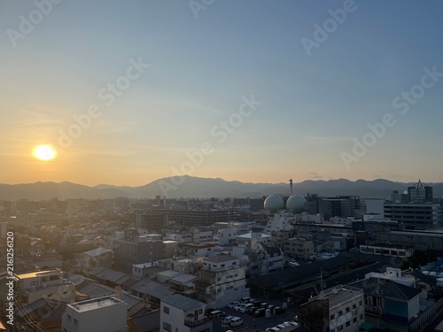 Tapety artystyczne 夕暮れの京都の街並み、太陽とガスタンク