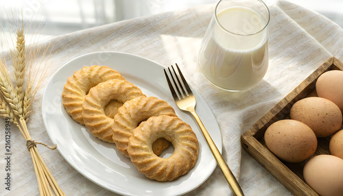Breakfast table with round butter cookies, fresh eggs and glass of milk.