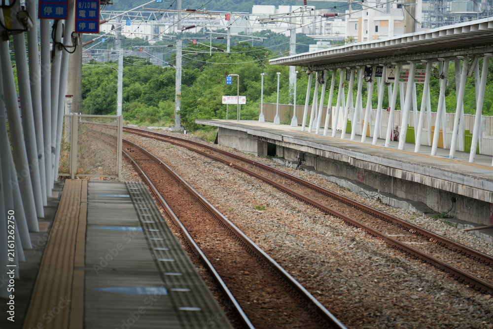 Fototapeta premium Empty railway platform and curved tracks extending forward.
