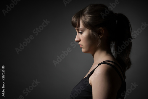 Portrait of a beautiful teenage girl posing in profile against a dark background