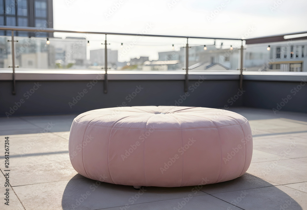 Fototapeta premium Rooftop lounge area with pink ottoman, urban outdoor living and relaxation space, modern city view background