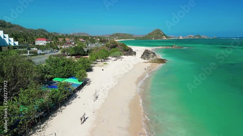Aerial drone view of Kuta Beach Lombok Indonesia on a sunny day showing white sand surf waves and turquoise ocean waters