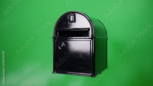 Black mailbox standing against a vibrant green background with cinematic camera rotation