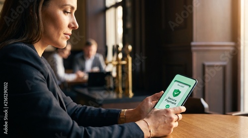 Professional Woman Making Secure Online Mobile Payment in Cafe