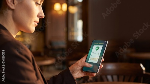 Woman using secure mobile payment app on smartphone in cafe