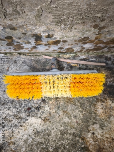 Yellow cleaning brush head lying on a textured concrete ground