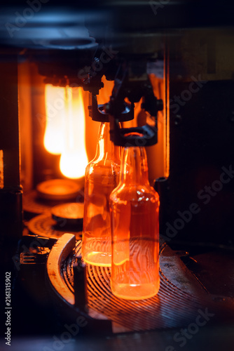 Close Up of Hot Glowing Glass Bottle in Forming Machine. Motion blur is used for dynamics.
