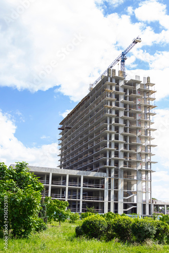 An unfinished high-rise building and three floors of a building. A green lawn.