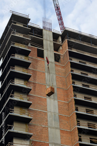 Construction of a house: panel floors and brickwork, a crane lifts a pallet with bricks.