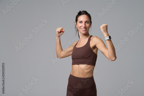 Happy athletic woman flexing muscles and smiling at camera in studio portrait