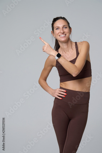 Fit woman pointing to side at copy space for advertising and text