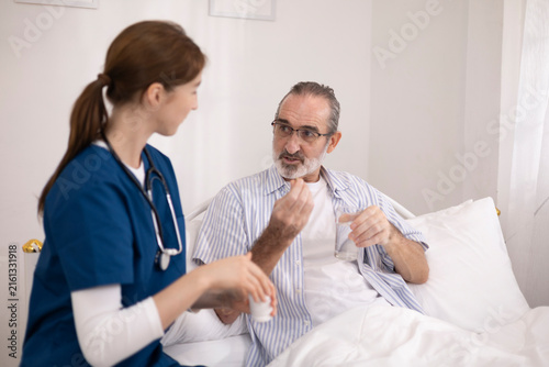 The elderly man was being cared for at home by a private nurse for his illness. The nurse brought him medication to take before bedtime and checked on his condition to monitor his health.