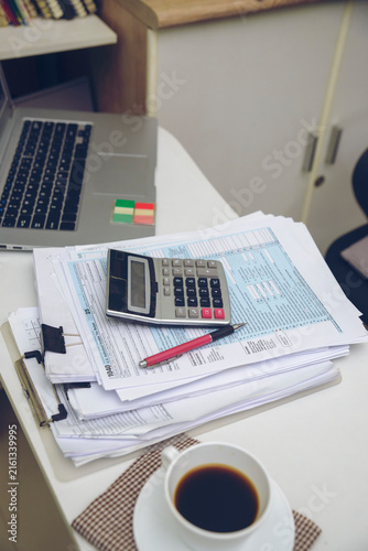 1040 tax form and calculator for tax calculation, accounting, budget planning, and financial paperwork, with a laptop and coffee on a home office desk-Vertical 