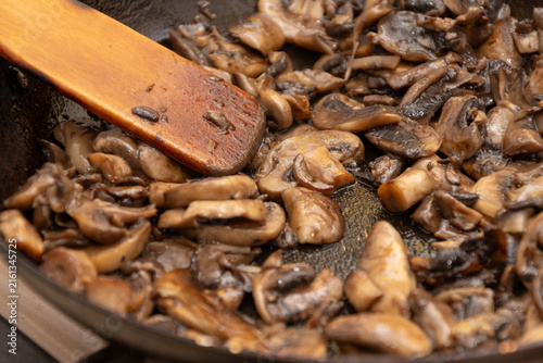 Cuadro en lienzo Closeup of saut ed sliced mushrooms cooking in pan with wooden spatula