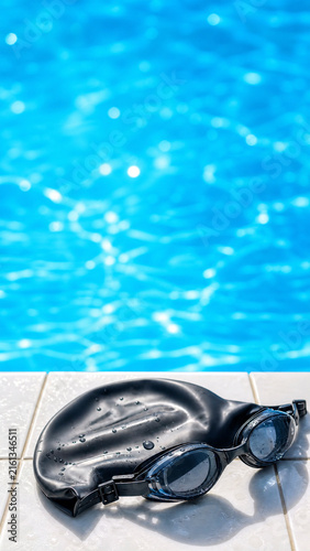 Vertical Instagram Story Background of Swim Goggles and Swim Cap on Pool Tile Edge with Shimmering Blue Water and Copy Space