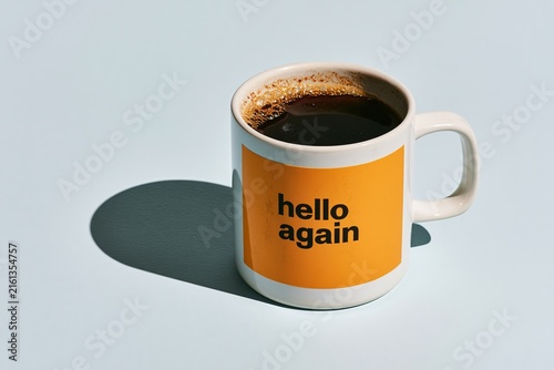 Coffee mug saying hello again on bright surface