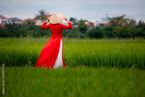 Foto Woman in traditional red ao dai in lush green field with rice hoi an vietnam