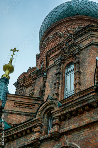 Canvas Print Low angle view focusing on the ornate red brick architecture, decorative window arch, and main green onion dome of Saint Sophia Cathedral in Harbin, Heilongjiang, China