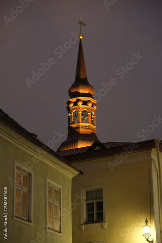 Low angle view of illuminated St. Nicholas Church spire in Tallinn Old Town at night.