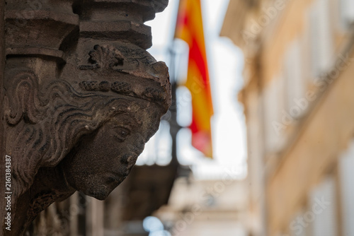 Fotografía Detailed Stone Carved Face Sculpture with Blurred Catalan Flag