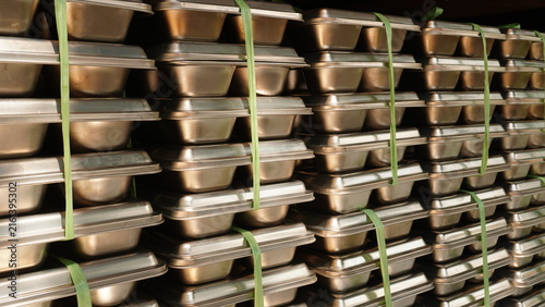 Foto Rows of stainless steel compartment food trays bound together by green raffia rope inside a shelf storage