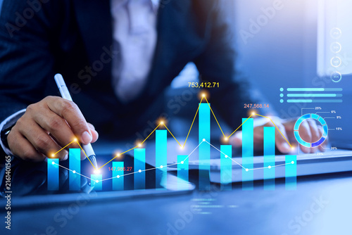 data analysis concept with businessman writing on dynamic financial graph curve and mark point on bar chart represents investment prediction data base