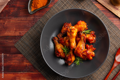 Spicy marinated chicken drumettes wing in black plate.Top view.