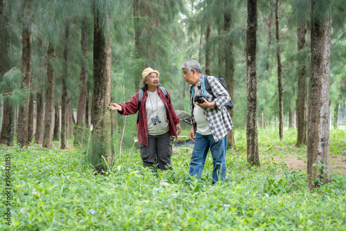 Canvastavla A healthy senior couple enjoys a relaxing nature walk while observing the surrounding forest with photography gear