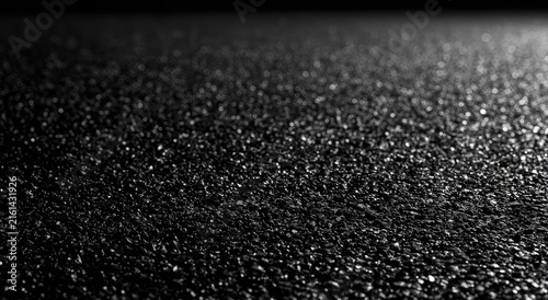 Close-up, low-angle view of dark, textured granular surface with subtle light