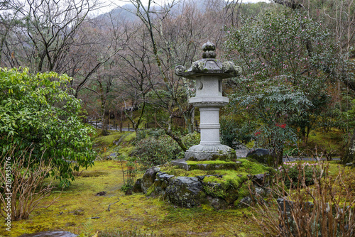 Traditional Stone Lantern on Moss Covered Rock in Japanese Garden with Misty Mountains