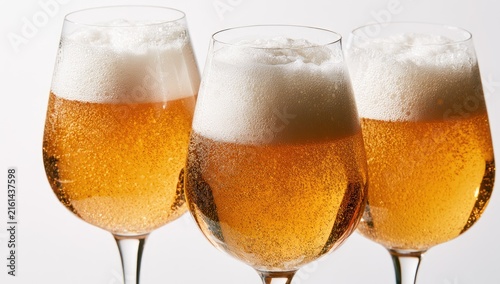 Three glasses of golden beer with frothy heads.