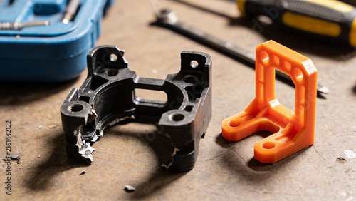 Printed orange bracket next to the broken original part