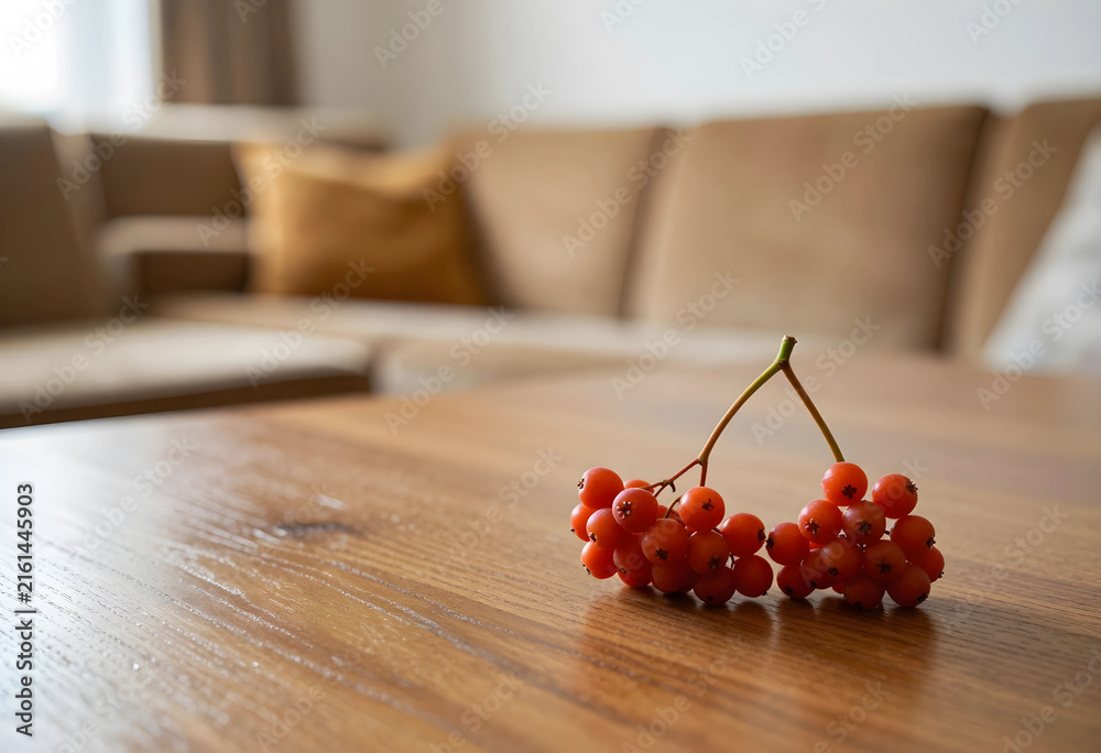 Fototapeta premium Autumn harvest and seasonal decor, red rowan berries on a wooden table in a cozy home interior with blurred background