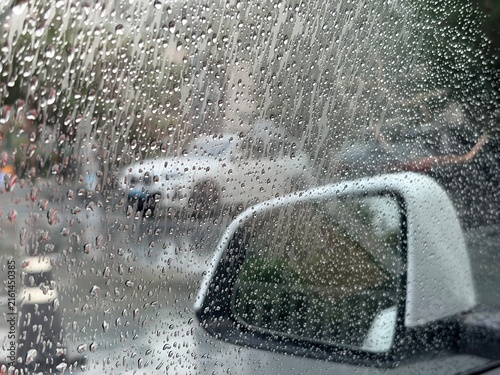 Cuadro en lienzo Raindrops running down a car side window with the wing mirror and blurred traffi