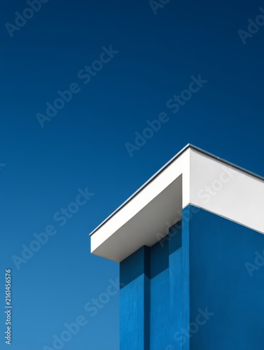 Modern blue building with white overhang against a clear blue sky