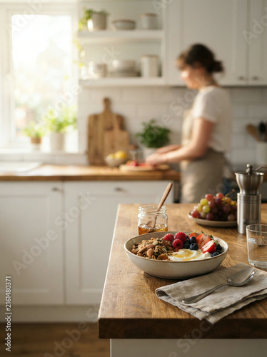 Yogurt bowl with granola berries and peach displayed on a wooden kitchen counter