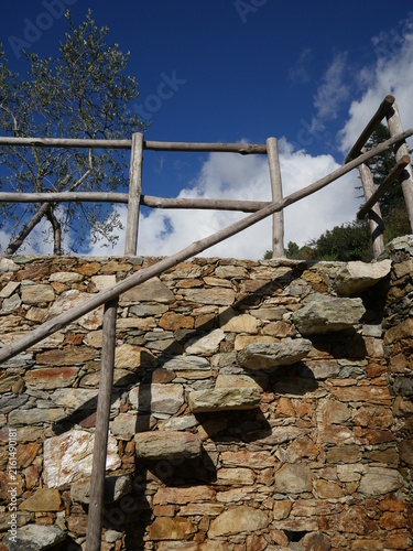 Stone wall with a wooden railing and a stone staircase