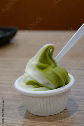 small cup of swirling matcha and vanilla soft serve ice cream, with a white plastic spoon