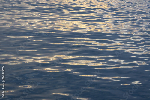 A close-up, full-frame shot of the ocean surface with light glinting off small, dark ripples.