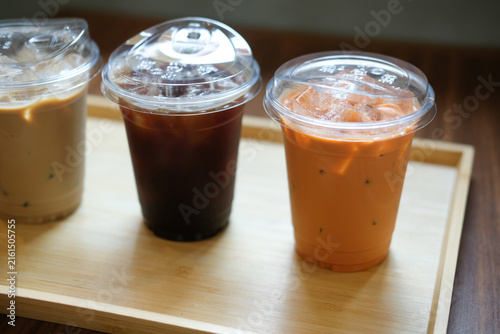 Three refreshing iced latte, iced Americano and an iced Thai milk tea served on wood tray