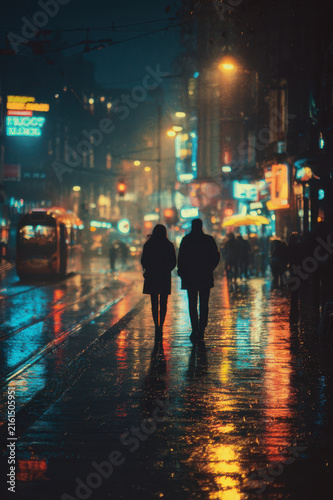 Couple walking on rainy city street at night