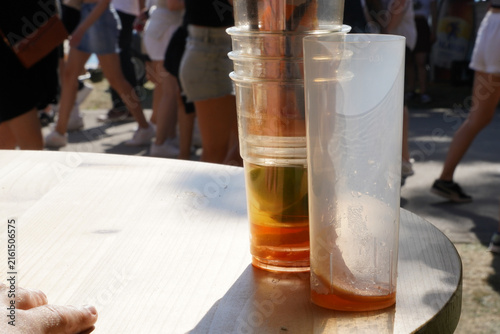 Plastic cups on outdoor table at summer event with people in background.