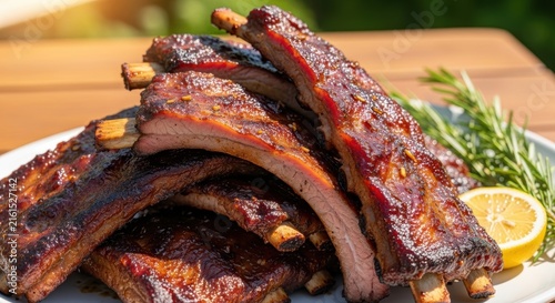 Succulent barbecue pork ribs with sauce lemon and rosemary on white plate.