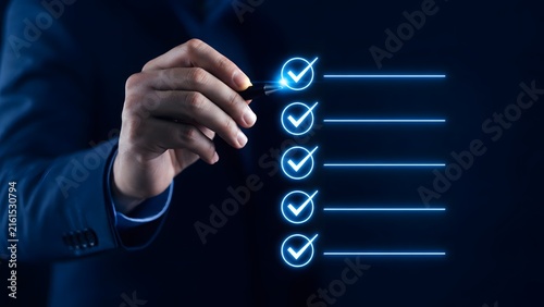 A business professional interacting with a glowing holographic image of a digital checklist to manage tasks and monitor progress in modern technology