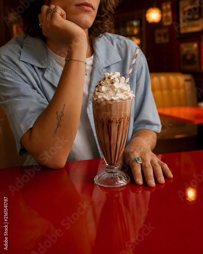 Woman with milkshake and whipped cream sitting in retro diner booth