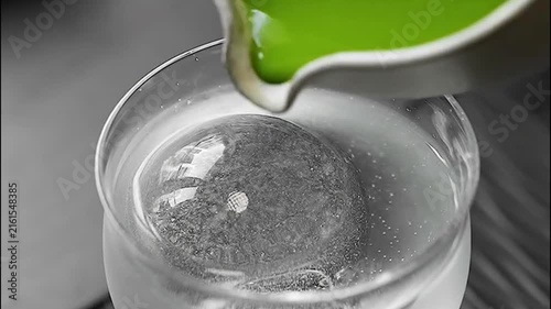 Pouring Concentrated Matcha Green Tea Over Ice Ball in Glass