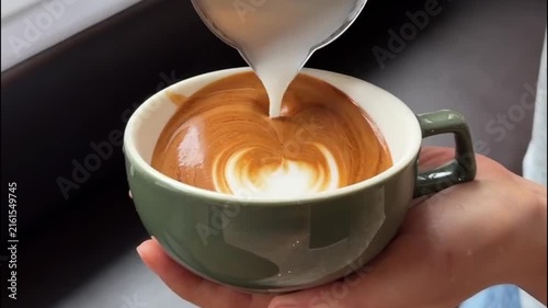 Barista Pouring Steamed Milk into Green Cup to Create Winged Heart Latte Art